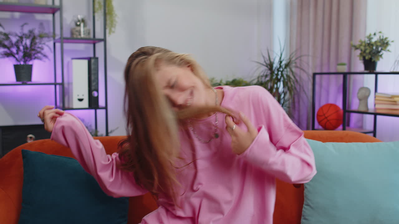 mujer joven llena de alegría mostrando un gesto de rock and roll, un signo fresco bailando regocijándose en el éxito en casa