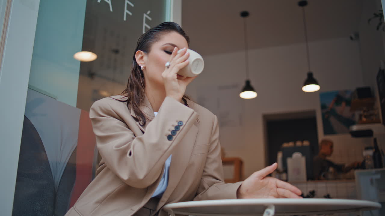 자신감 넘치는 사업가 여성이 쾌적한 레스토랑에서 커피를 즐기고 있습니다. 우아한 여성
