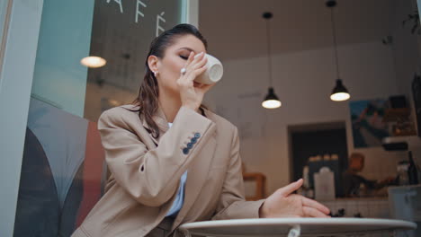 una mujer de negocios confiada disfruta del café en un acogedor restaurante de cerca.