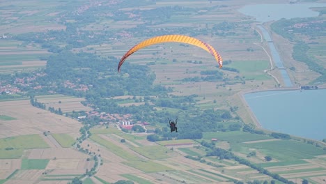 paragliders float gracefully in the wind, surrounded by a bright, clear sky and a stunning landscape below.