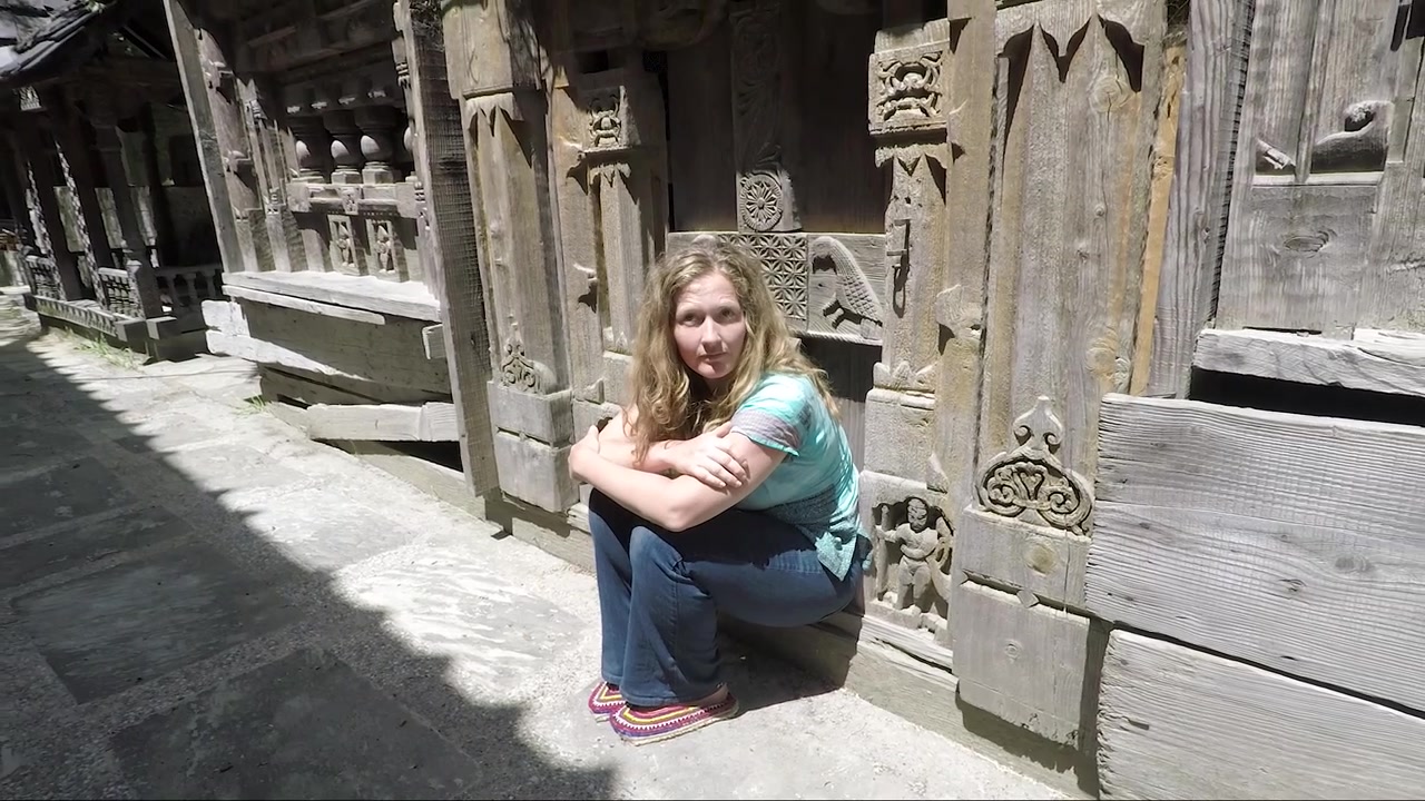 Bela mulher caucasiana sentada na porta de um templo himalaio. Plano sequência estável.