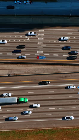 cars moving quickly by the wide-lane road to both sides. drone footage above the highway with heavy traffic at daytime. vertical video