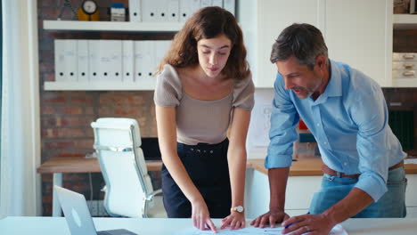 arquitectos masculinos y femeninos con computadoras portátiles se reúnen y discuten planes de construcción en una oficina moderna