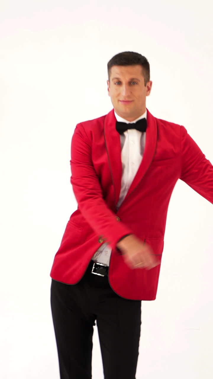 funny man in red suit is making funny movement with his hands and body on a white background in the studio. Fool around Vertical video
