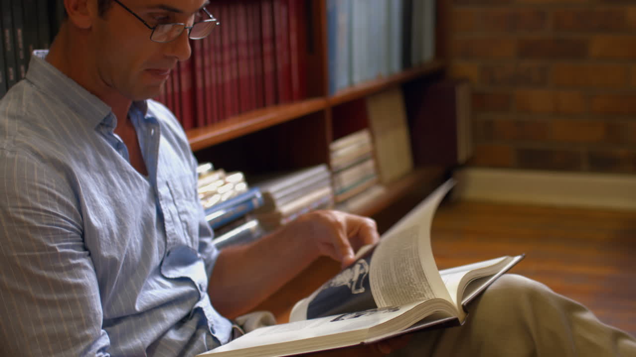 estudiante sentado en el suelo leyendo en la biblioteca