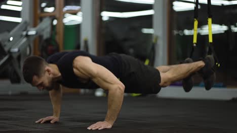 sportsman doing flooring abs exercises with trx straps at gym