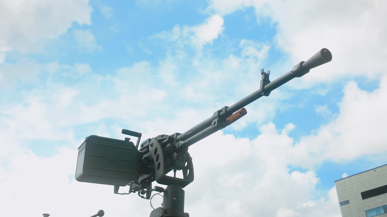 Un'inquadratura dal basso di una mitragliatrice di grosso calibro montata su una torretta di veicolo blindato, adatta per contenuti documentaristici di difesa e militari