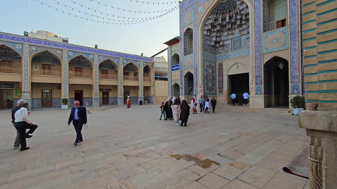 Pessoas caminhando no pátio de uma Mesquita Iraniana Tradicional.