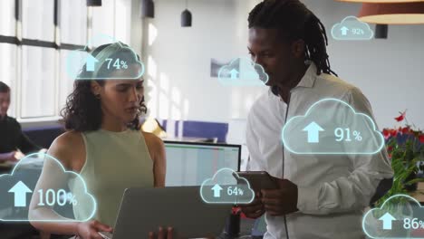 Animation-of-cloud-icons-with-increasing-percentage-over-diverse-man-and-woman-discussing-at-office