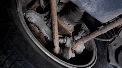 dirty underside of a car with rusty metal and suspension. rotating moving shot in 4k.