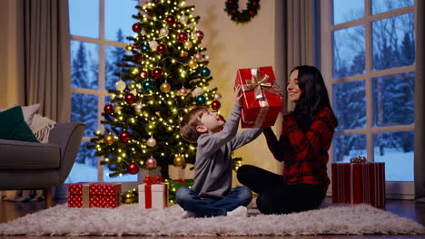 mother and son exchanging gifts by the christmas tree