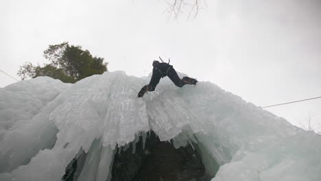 looking directly up as a person ice climbing a sheer frozen rock face