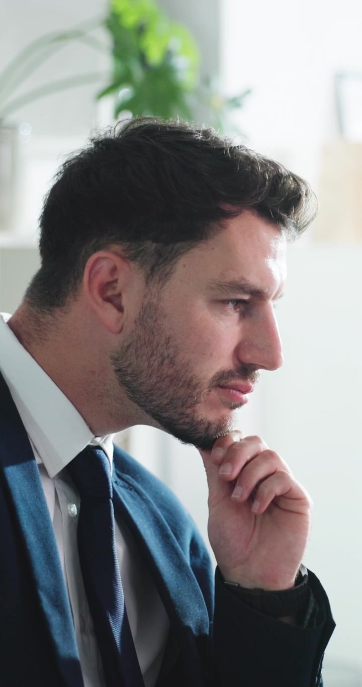 Uomo d'affari stressato che pensa e si strofina la fronte in ufficio