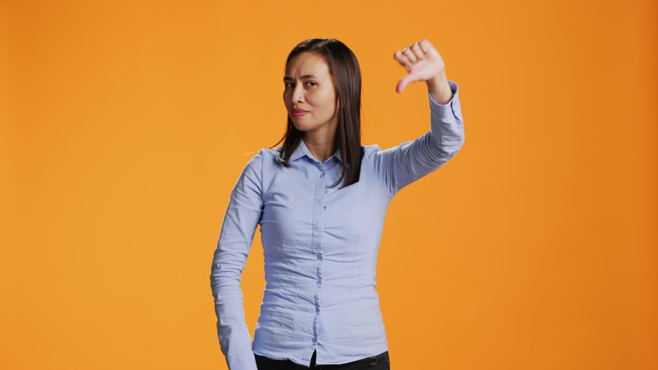 아시안 모델이 스튜디오에서 혐오 기호를 보여줍니다.