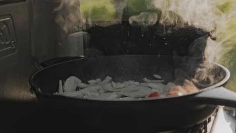 person pouring organic oil over fried onion and vegetables, preparing delicious dinner