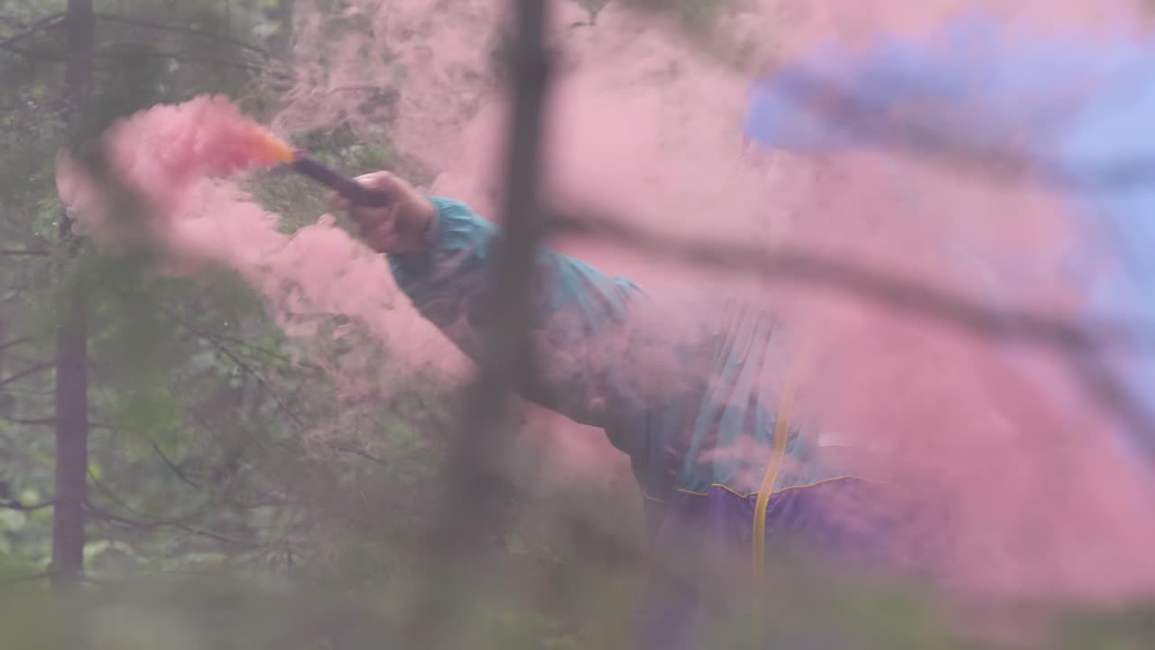 persona que libera humo rosa y azul en un bosque