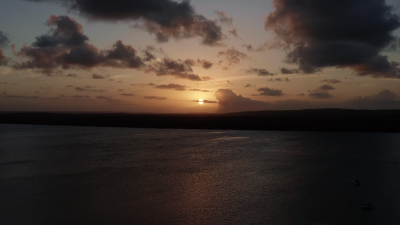Trucking right aerial shot of a golden sunset from the famous alligator beach, a river in Cabedelo, Paraiba, Brazil, near the coastal capital city of Joao Pessoa, revealing a group of tour boats