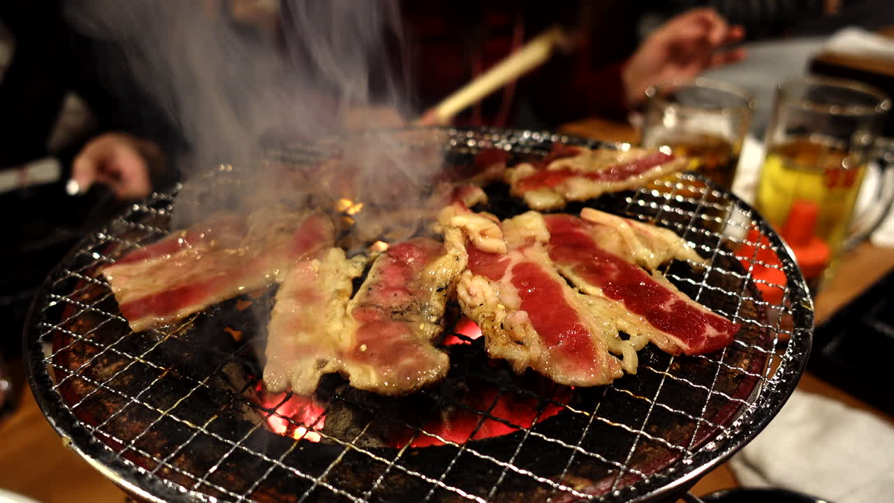 Closeup of traditional Japanese barbecue charcoal grill fire with delicious fresh steaming meat zoom out shot