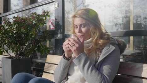 Happy-young-woman-drinks-coffee-while-soaking-in-warm-morning-sun