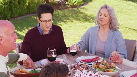 Happy-caucasian-family-praying-before-dinner-in-garden