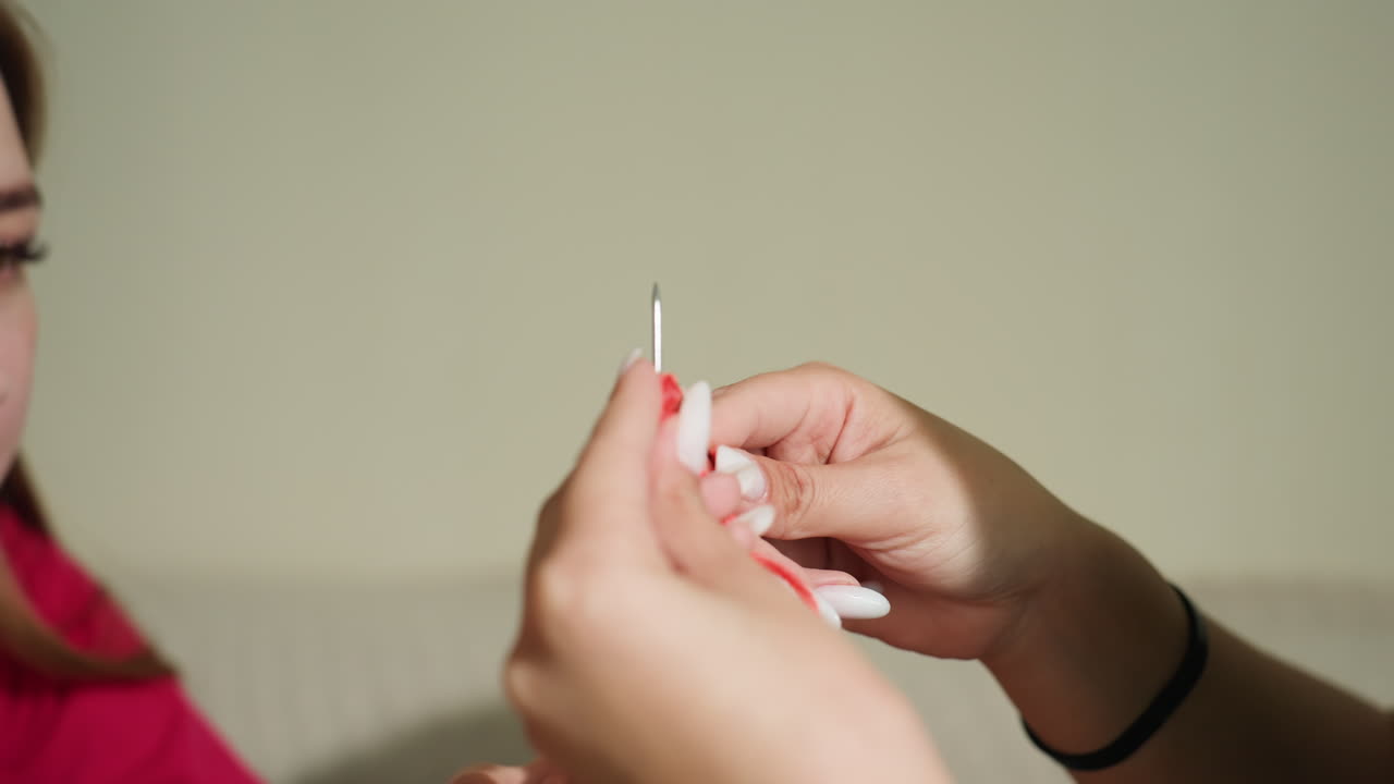 manos artesanas trabajando con atención, vista detallada de unas manos que hábilmente enhebran hilo a través de una aguja de ganchillo, primer plano de unos dedos que manipulan cuidadosamente el hilo para crear intrincados puntos de ganchillo