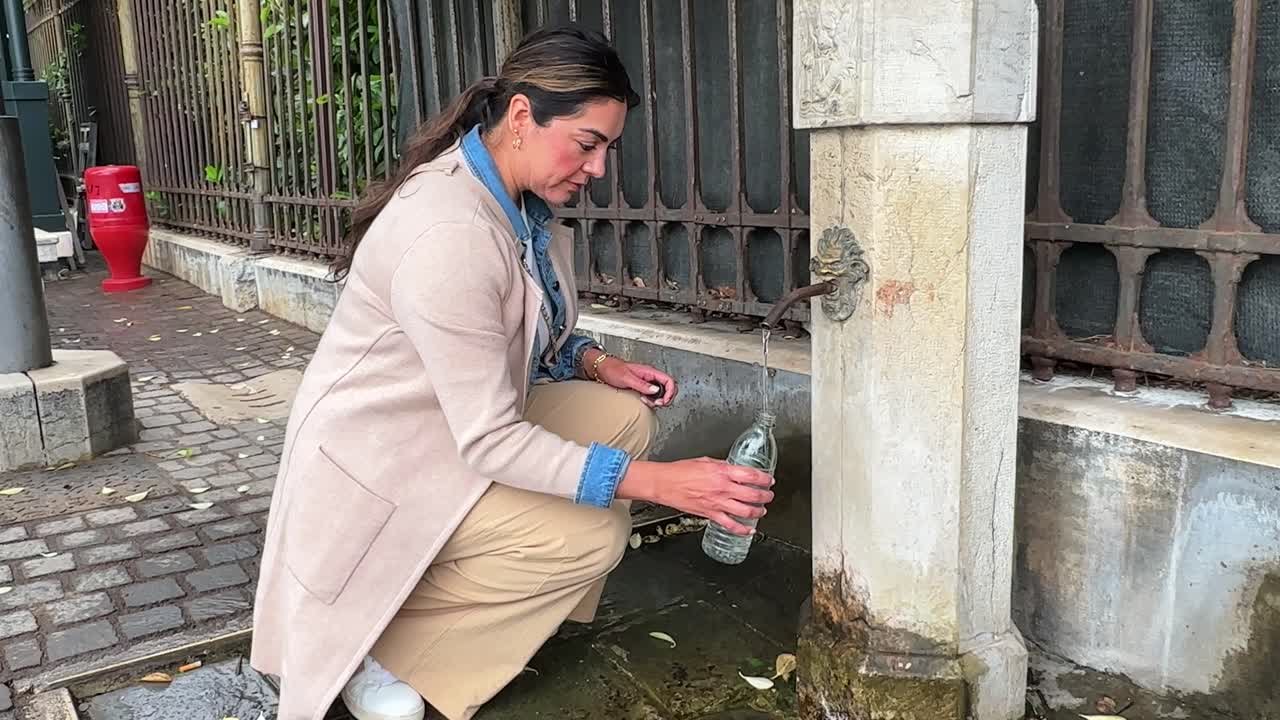 여성 관광객이 이탈리아 베네치아의 공공 음료 분수에서 물 병을 채운다.