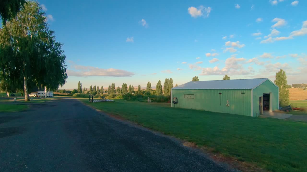 granero verde y carretera asfaltada al borde de un complejo de rv con algunos invitados a última hora de la tarde