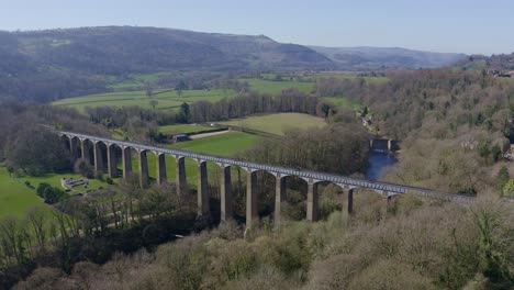 people walk across the beautiful narrow boat canal route called the pontcysyllte aqueduct famously designed by thomas telford, located in the beautiful welsh countryside, a huge bridge viaduct