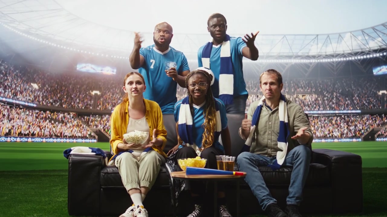 Aficionados al fútbol estresados viendo un partido dramático en casa durante una transmisión inmersiva.