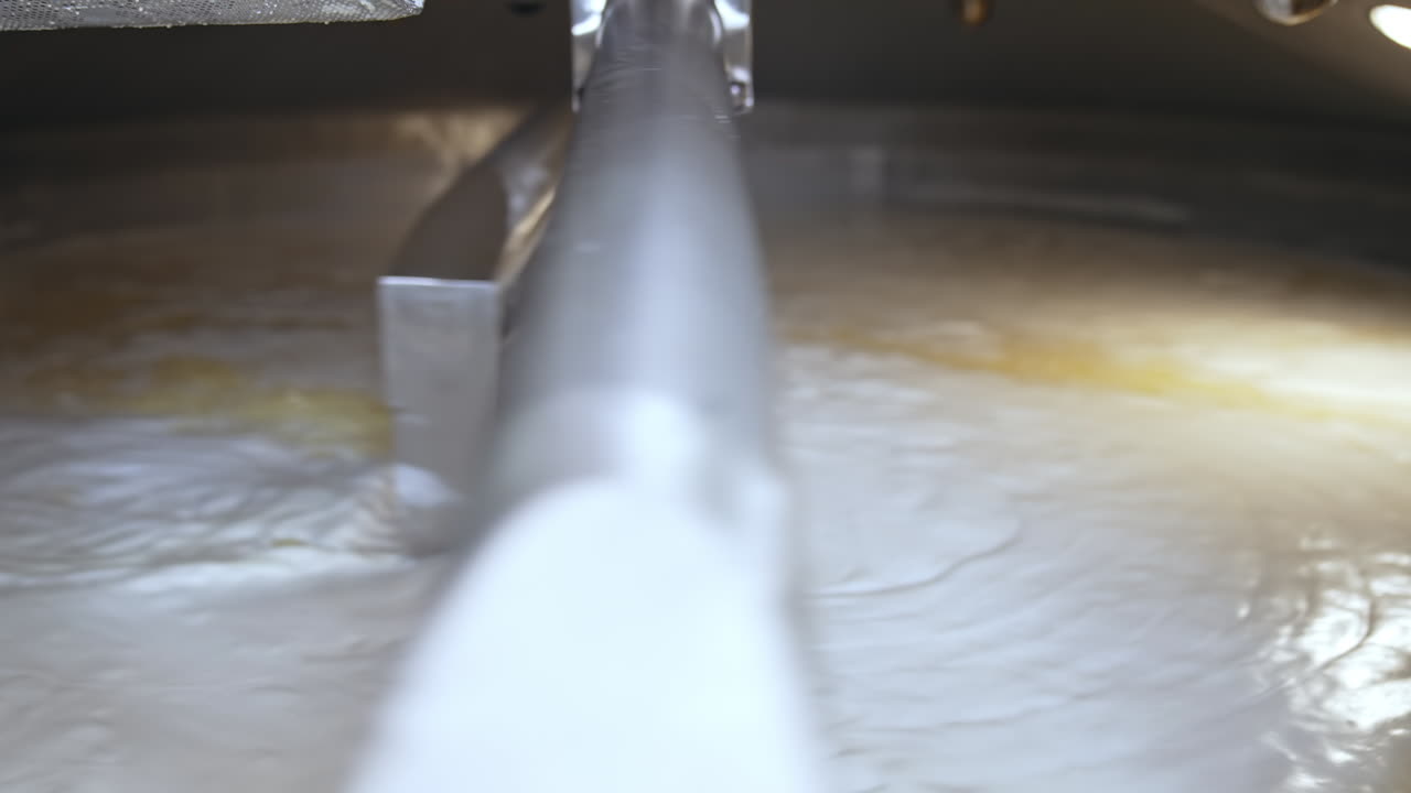 Two big automatic nozzles turning and mixing the dairy product. Fermented milk being mixed up in a big tank. Butter and cheese manufacturing at modern plant.
