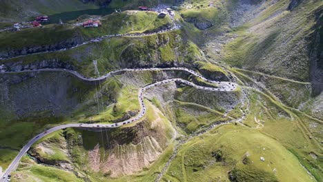 cinematic-aerial-dolly-tilt-up-above-Transfagarasan-Serpentine-Road-and-electricity-pylons,-traffic-stopped-at-pull-offs