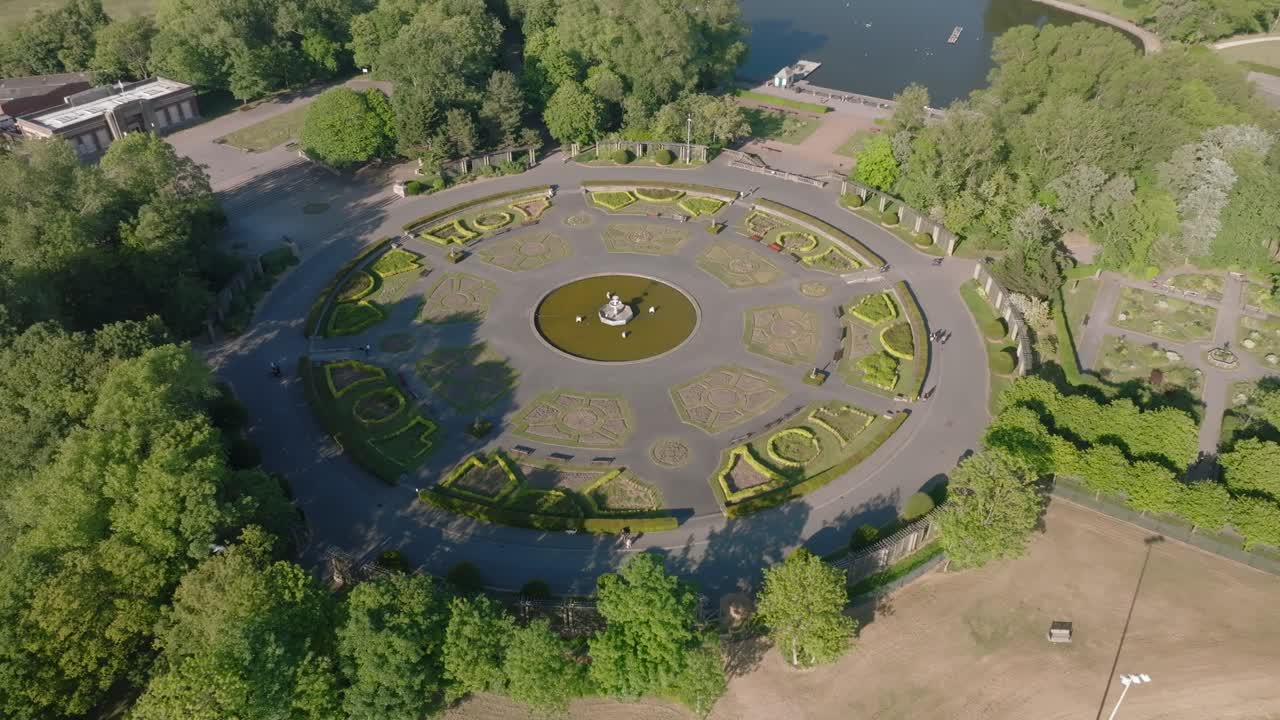 Circular Italian style gardens next to parkland lake. Slow orbit. Stanley Park, Blackpool, Lancashire, UK.
