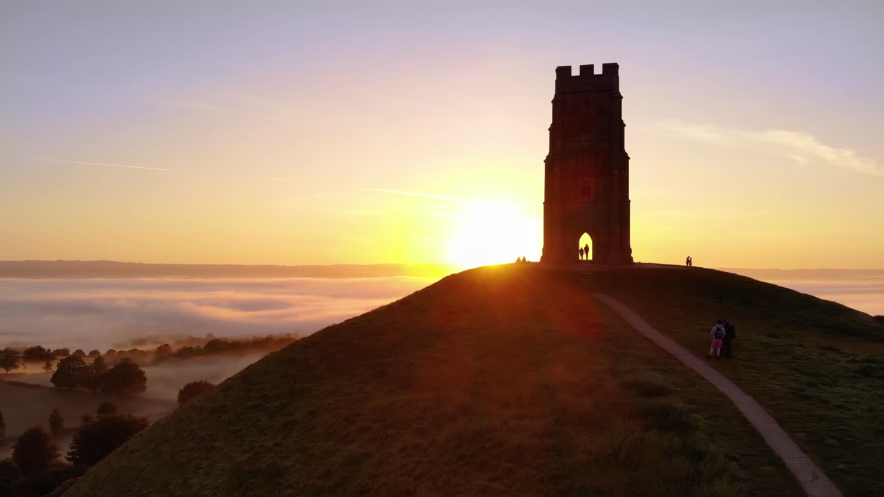 El amanecer dorado apareciendo detrás de Glastonbury Tor y revelando los campos brumosos de abajo