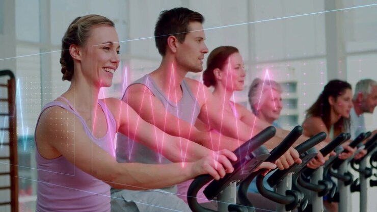 Riders on bikes in gym studio, pedaling motion initiating ECG grid overlay boosting cardio fitness