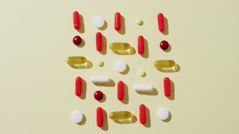 Video-of-a-variety-of-pills-and-capsules-arranged-on-yellow-background-with-copy-space