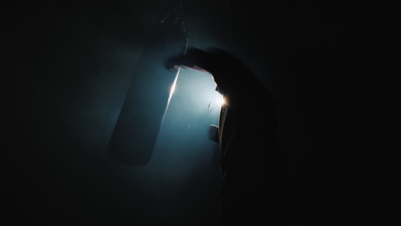 Silhouette di un combattente Trinity in palestra - colpisce un sacco da boxe.