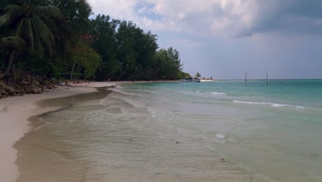 Un-Tranquilo-Paseo-Por-La-Orilla-Arenosa-De-La-Playa-De-Malibu-En-Koh-Phangan,-Tailandia,-Con-Aguas-Turquesas-Y-Exuberante-Vegetación