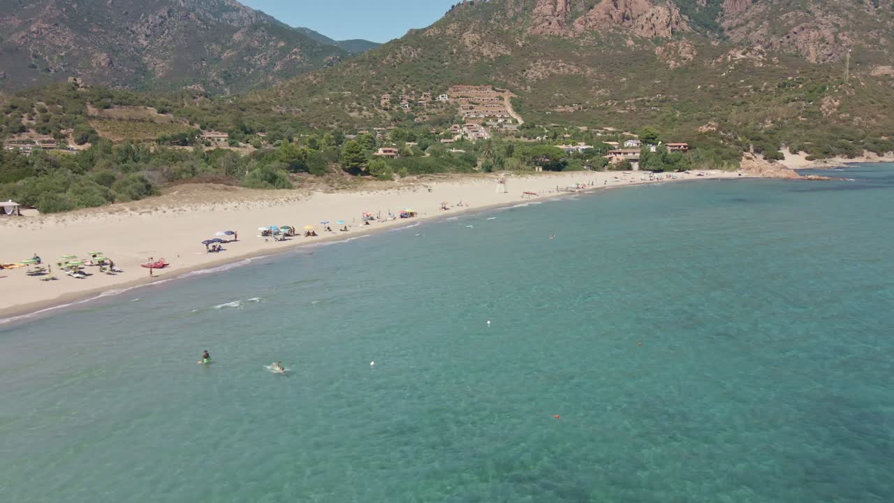 Aerial Drone Slide View of Tropical Sea with People Swimming and Umbrellas at Beach