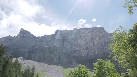 a gorgeous young hiker woman in hiking gear and a pink t-shirt is walking her way up the hike to refuge de salles, sixt-fer à cheval in front of a magnificent cliff
