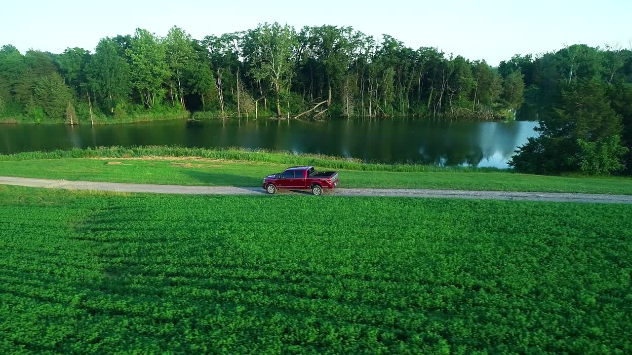 Red pickup truck on a country road by the lake