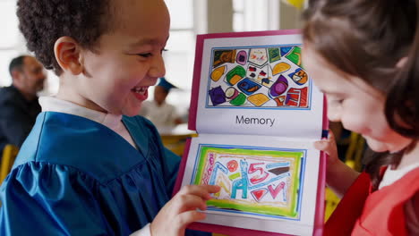 children at preschool graduation looking at a memory book