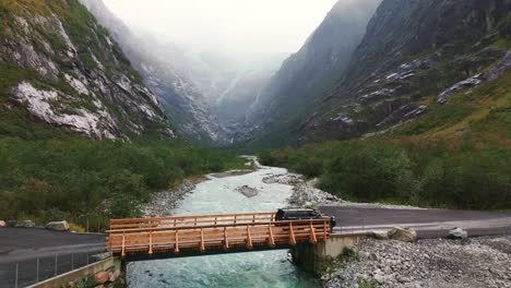 car crossing a bridge with the kjendalsbreen glacier in the background (drone footage)