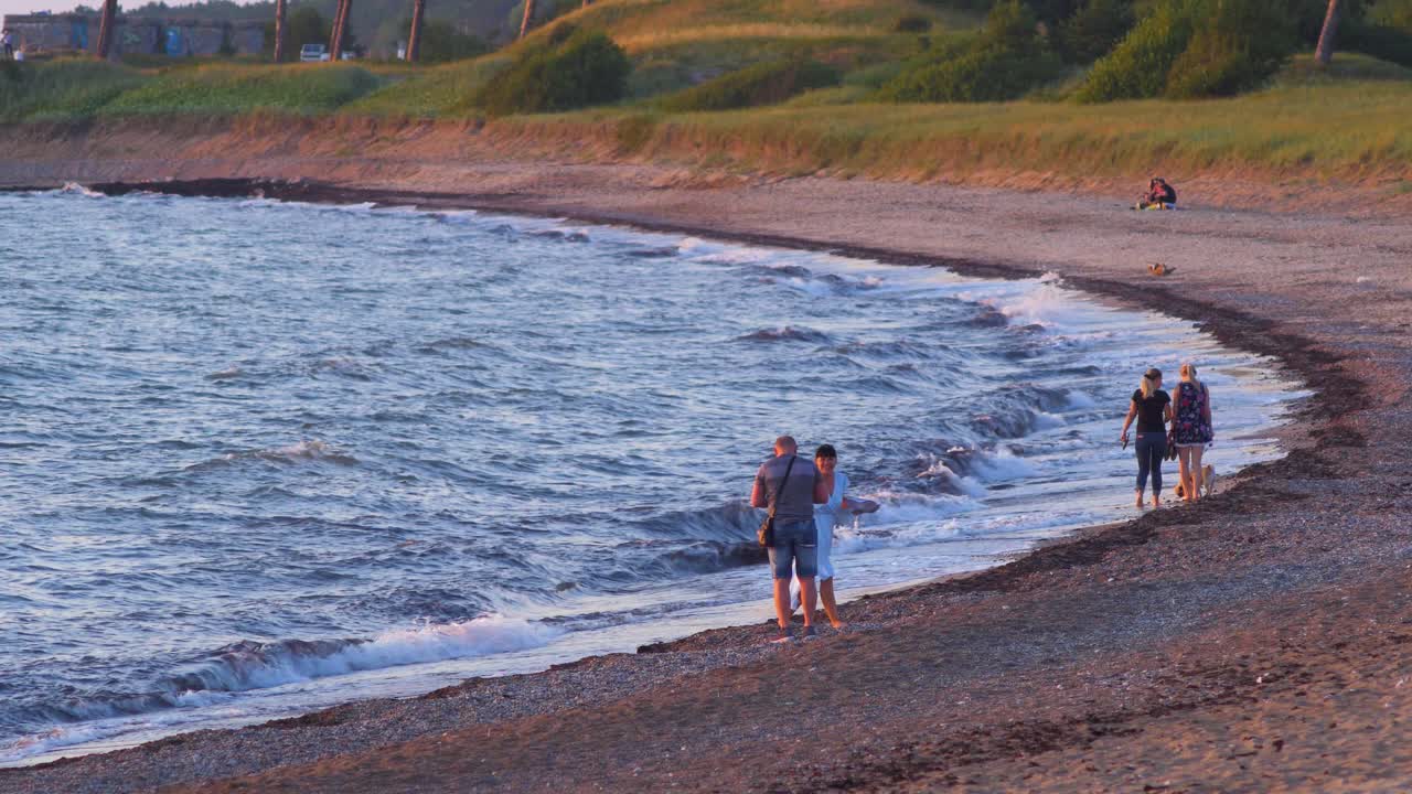 People Enjoying a Sunset Walk Along the Beach