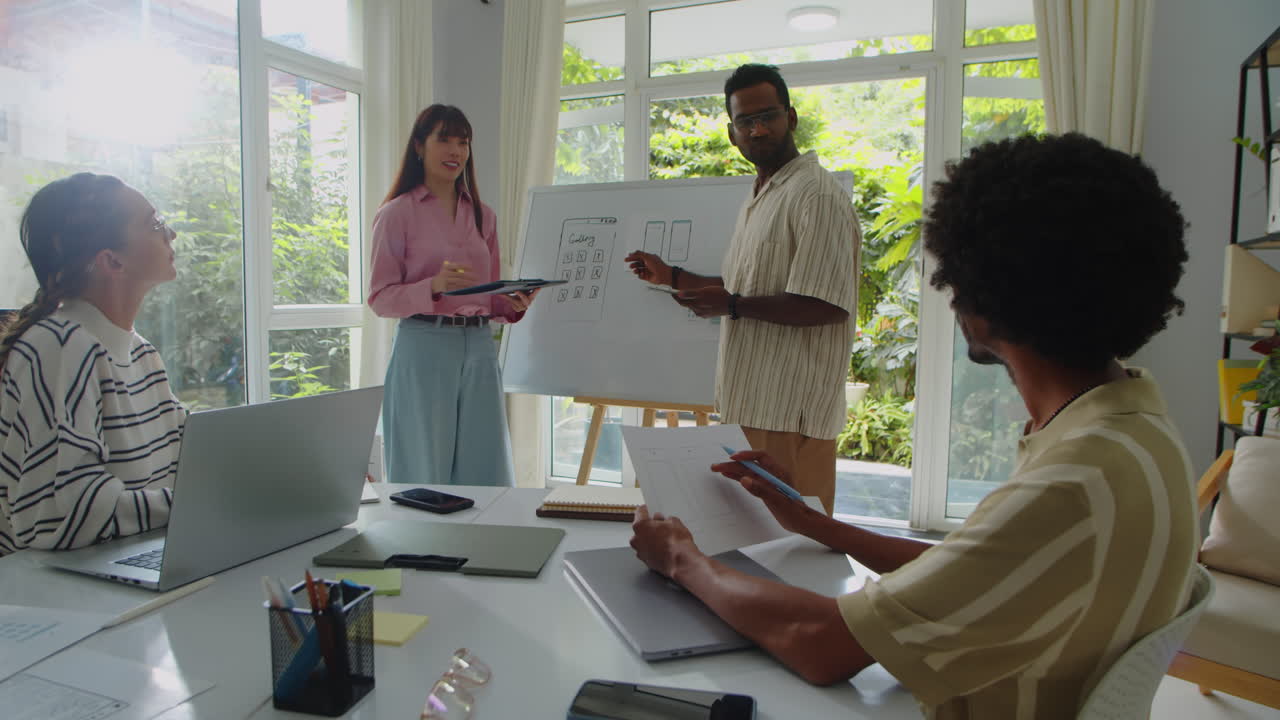 Diverse Coworkers Standing near Whiteboard with App Design during Office Meeting