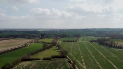 Vista-Aérea-Sobre-Campos-Verdes-Con-Cielo-Nublado-Claro