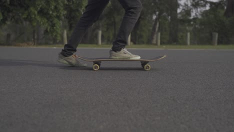 a dynamic ground-level lateral shot following beside a skater as he rides his skateboard and performs kicks to move it around