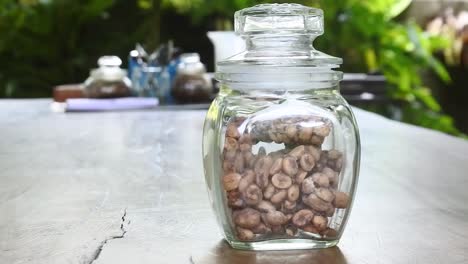 Pan-right-shot-of-authentic-Indonesian-luwak-coffee-in-a-glass-jar-on-a-wooden-table