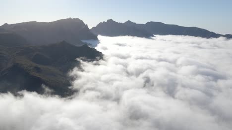 Volando-Por-Encima-De-Las-Nubes---Vista-Asombrosa-De-Las-Nubes-Y-El-Pico-De-Las-Montañas-En-Un-Día-Soleado