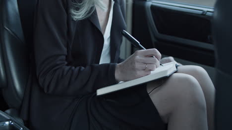 businesswoman writing on a notebook in a car