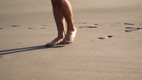 close up of male feet walking on beach